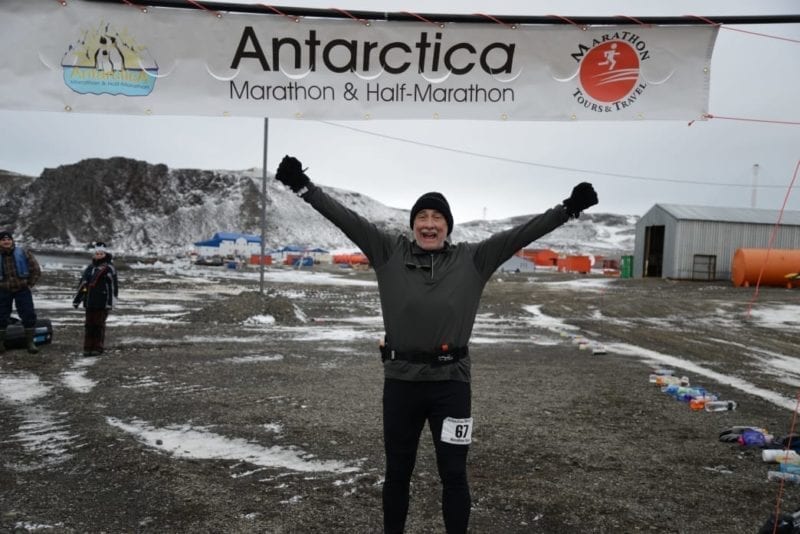 Truman Smith under Antarctica banner finishing a marathon