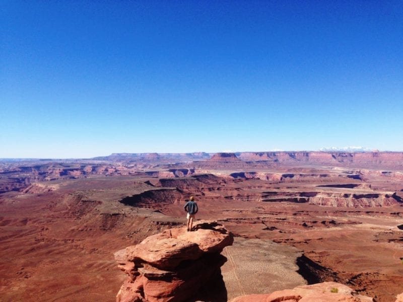 Person standing atop desert rock.